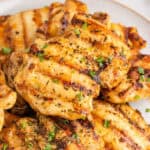 square image of grilled chicken thighs on a plate