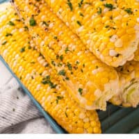 grilled corn on the cob stacked on a blue platter with recipe name at the bottom