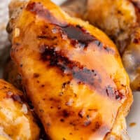 close up of one grilled honey hot wings with the title of the post on top of the image in pink and black lettering