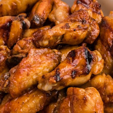 square close up image of grilled honey sriracha chicken wings in a serving bowl