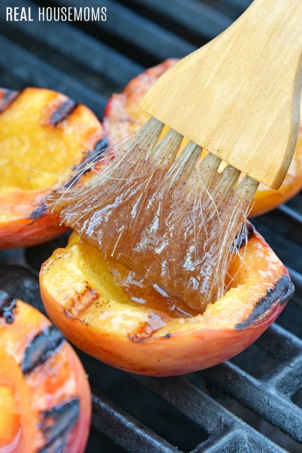 basting brush coating peach halves on the grill