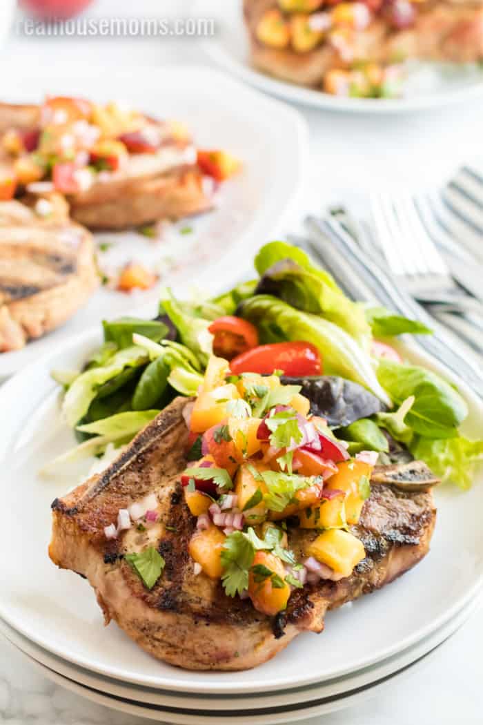 pork chops served with salad, rice, and peach salsa