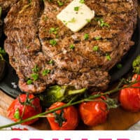 grilled ribeye steaks topped with butter and herbs on a platter with recipe name at the bottom