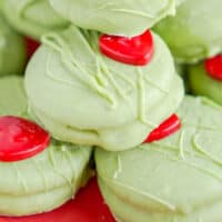 grinch chocolate covered oreos piled on a red plate with recipe name at the bottom