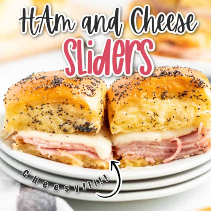 square image of two ham and cheese sliders side by side on top of a stack of plates