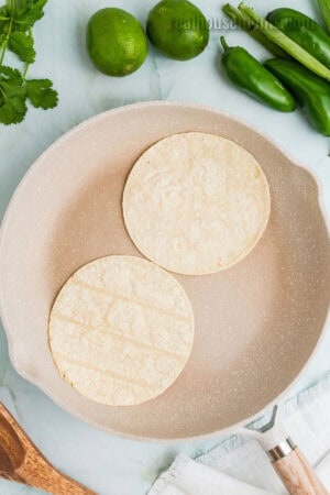corn tortillas being toasted in a dry skillet