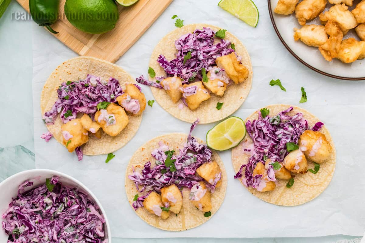 looking down at halibut tacos open flat on parchment paper after assembling