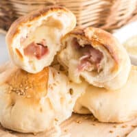 ham & cheese stuffed biscuits piledup in a basket with one broken op to show filling with recipes name at bottom