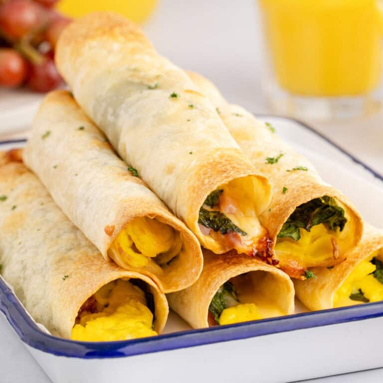square image of ham & egg breakfast taquitos piled on a serving platter