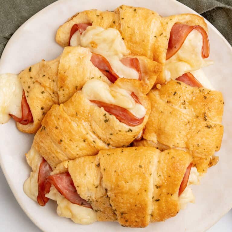 square image of ham and cheese crescent rolls piled on a plate