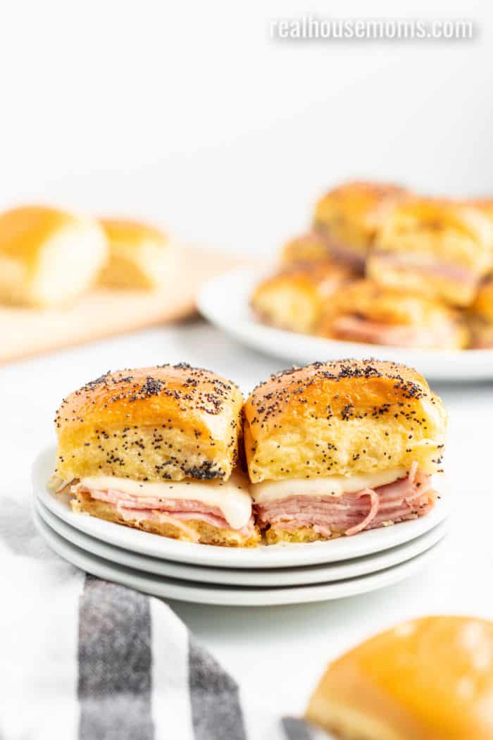 two ham and cheese sliders side by side on a plate showing the sandwich layers