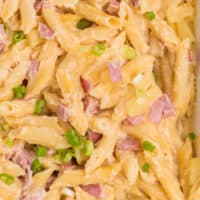 close up of ham and pineapple pasta bake with green onions on top with recipe name at bottom