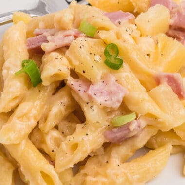 square close up image of ham and pineapple pasta bake on a plate