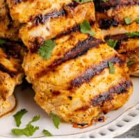 close up of grilled harissa chicken on a plate with recipe name at the bottom