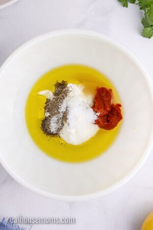 ingredients to make harissa marinade in a large white mixing bowl