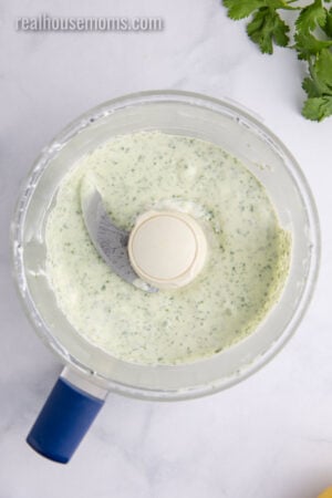 cilantro yogurt sauce in a food process bowl after being mixed