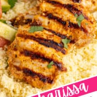 harissa chicken plated over couscous next to cucumber tomato salad with the title of the post diagonal on the bottom right with pink and black lettering and highlights