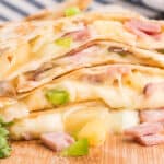 square image of hawaiian quesadillas stacked up with cheese oozing out the sides