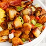 square image of home fries on a plate with bacon and eggs