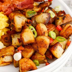 square image of home fries on a plate with bacon and eggs