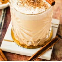 homemade eggnog in a glass with a cinnamon stick with recipe name at the bottom