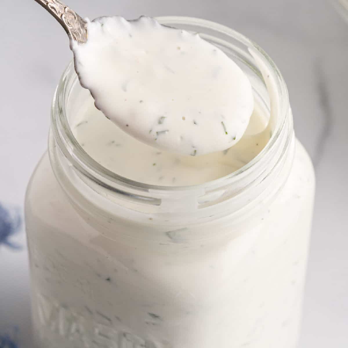 square image of homemade ranch dressing on a spoon over a mason jar