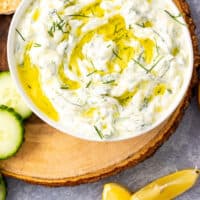 homemade tzatziki sauce in a bowl topped with olive oil and dill with recipe name at the bottom