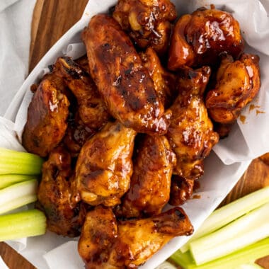 square image of a basket of honey bbq chicken wings with celery sticks