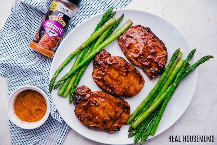 Honey BBQ pork chops on a plate with grilled asparagus