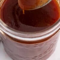 honey barbecue sauce on a spoon over a jar with recipe name at the bottom
