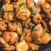 spoonful of honey butter chicken over the skillet with recipe name at the bottom