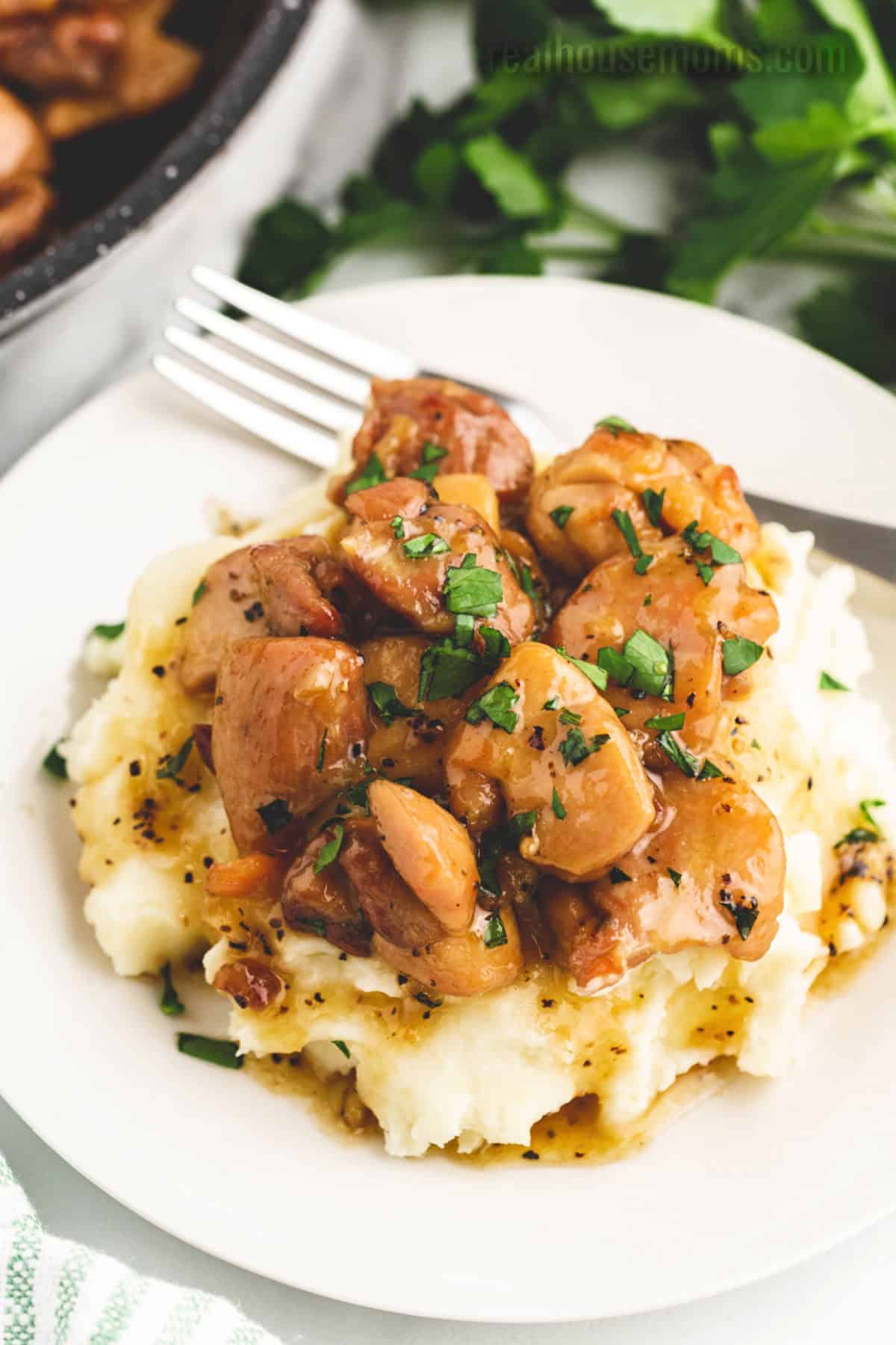 Honey Butter Chicken is better than take-out! If you want a quick and easy dinner then look no further than this juicy, sweet chicken dish! honey butter chicken served over mashed potatoes on a plate with a fork