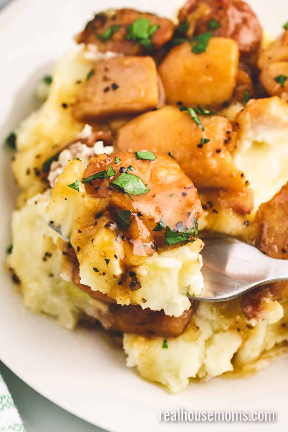 Honey Butter Chicken is better than take-out! If you want a quick and easy dinner then look no further than this juicy, sweet chicken dish! forkful of honey butter chicken and mashed potatoes over the plate