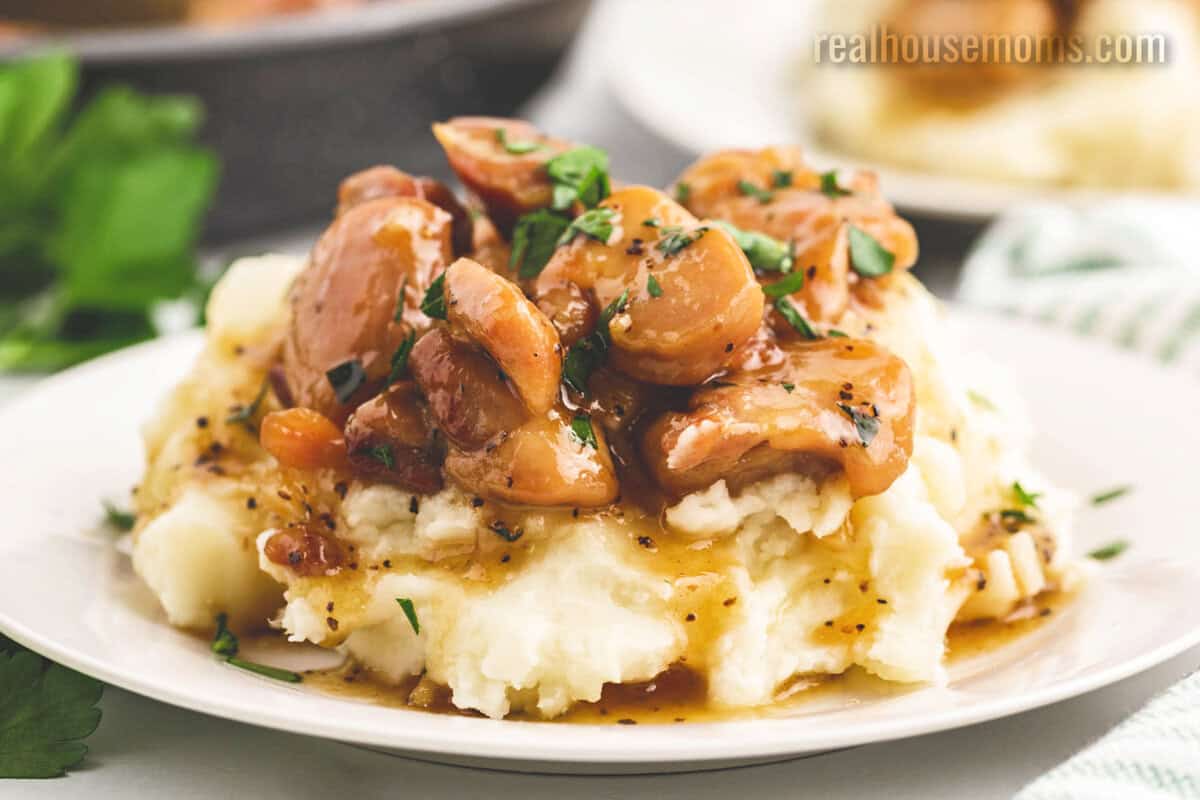 honey butter chicken served over mashed potatoes on a white plate