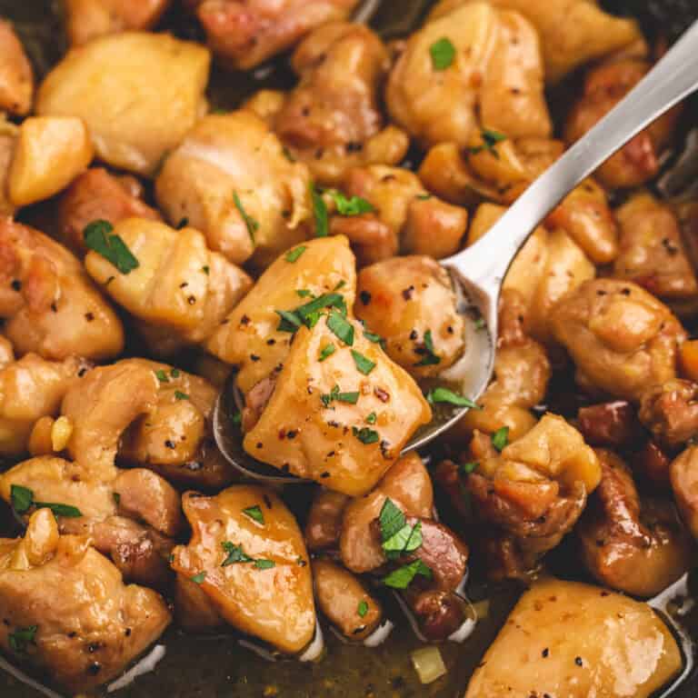 square image of a spoonful of honey butter chicken with chopped parsley over the skillet