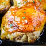 square image of a hony garlic chicken thigh in a skillet