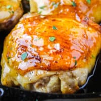 square image of a hony garlic chicken thigh in a skillet