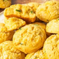 image of honey jalapeno cornbread drop biscuits piled on a plate with the title of the post on top of the image in blue and blsack lettering