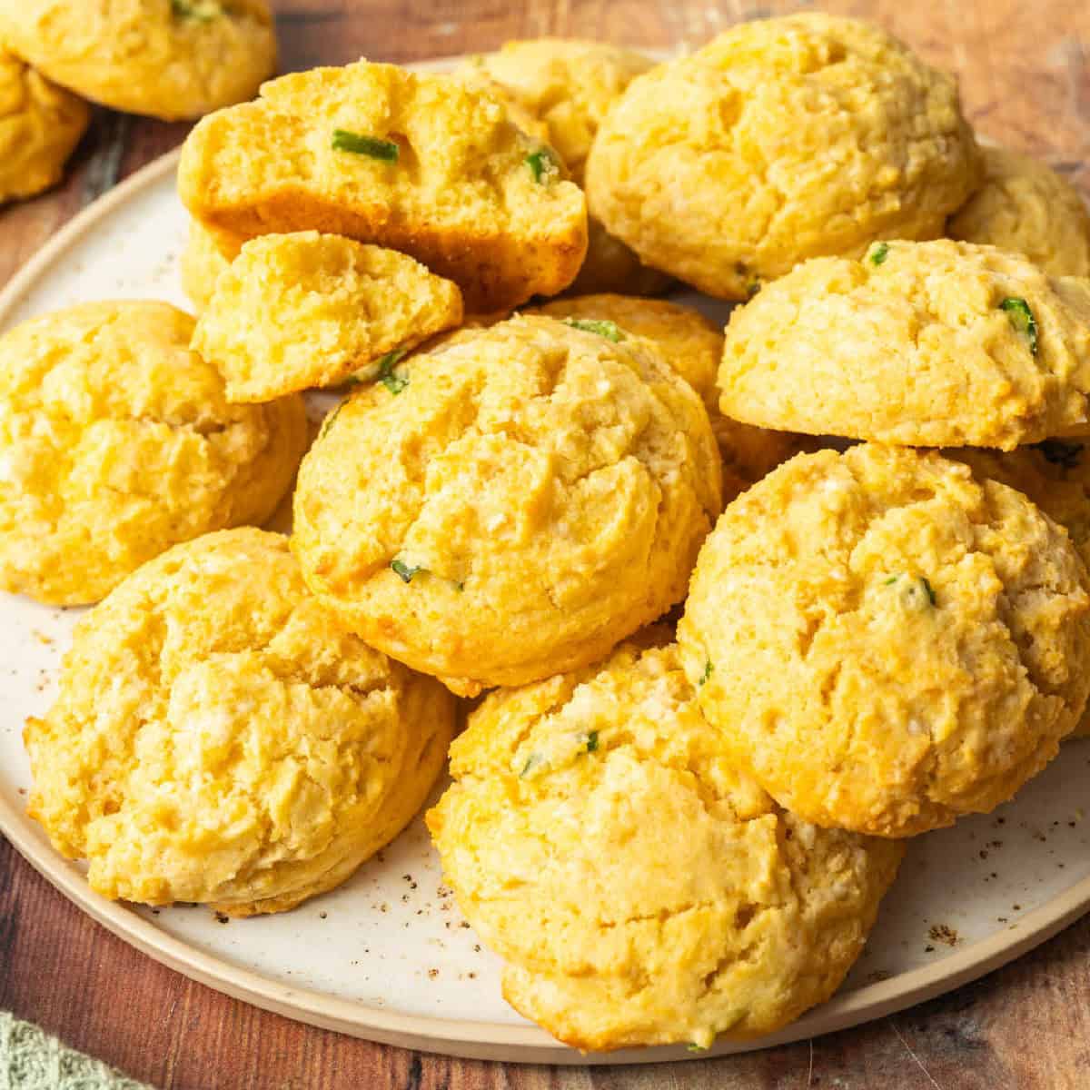 square image of honey jalapeno cornbread drop biscuits piled on a plate