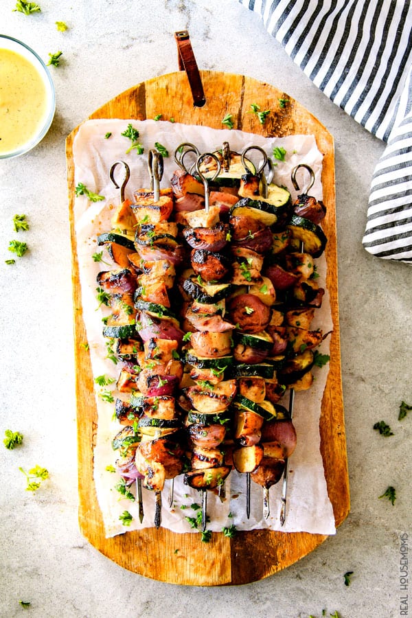 Honey Mustard Chicken Kabobs stacked up on a wooden serving tray with honey mustard dipping sauce.