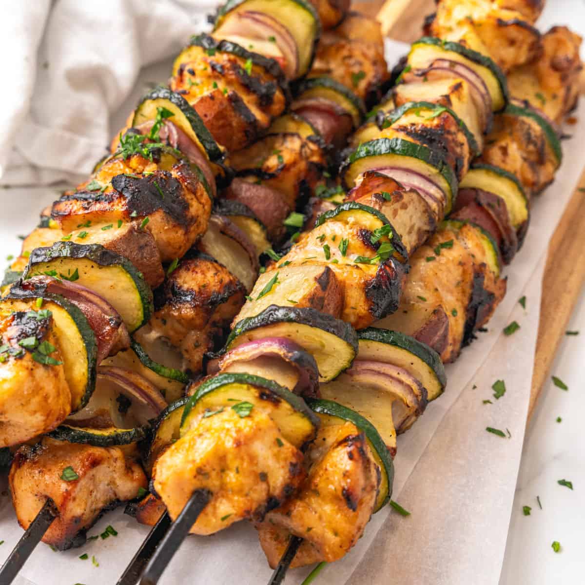 square image of honey mustard chicken kabobs piled on a cutting board