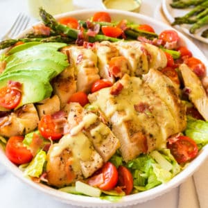 honey mustard chicken salad in a bowl with avocado, asparagus, and tomatoes