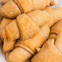 image of a plate of honey wheat dinner rolls with the title of the post on top of the image in pink and black lettering