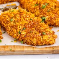 hot honey cornflake chicken on a parchment paper lined wooden board with recipe name at the bottom