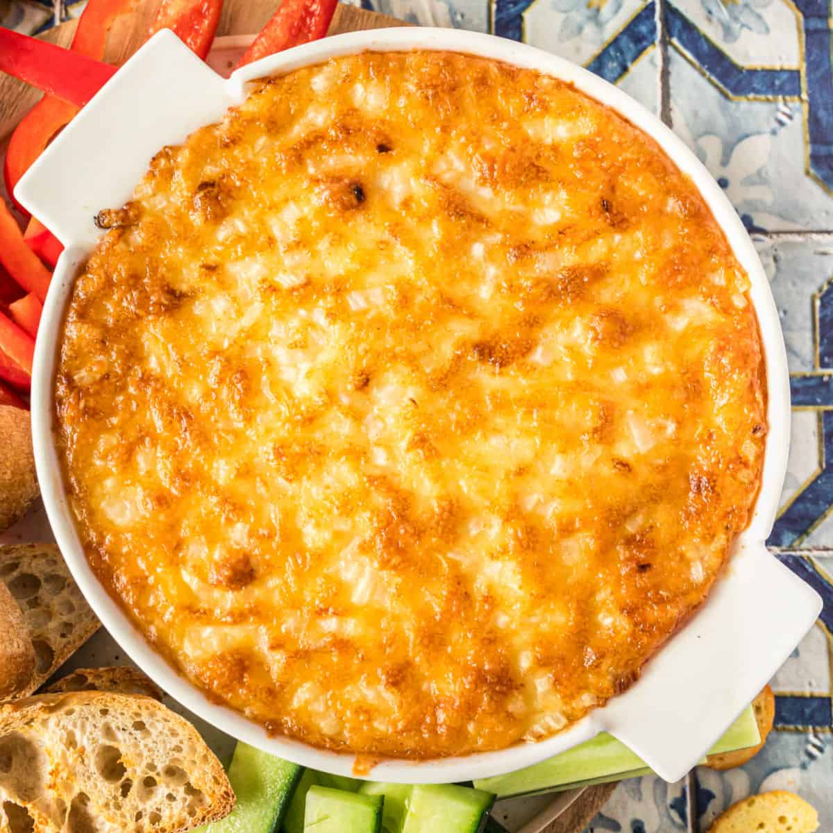 square image of hot onion & cheese dip with golden brown top in a casserole dish