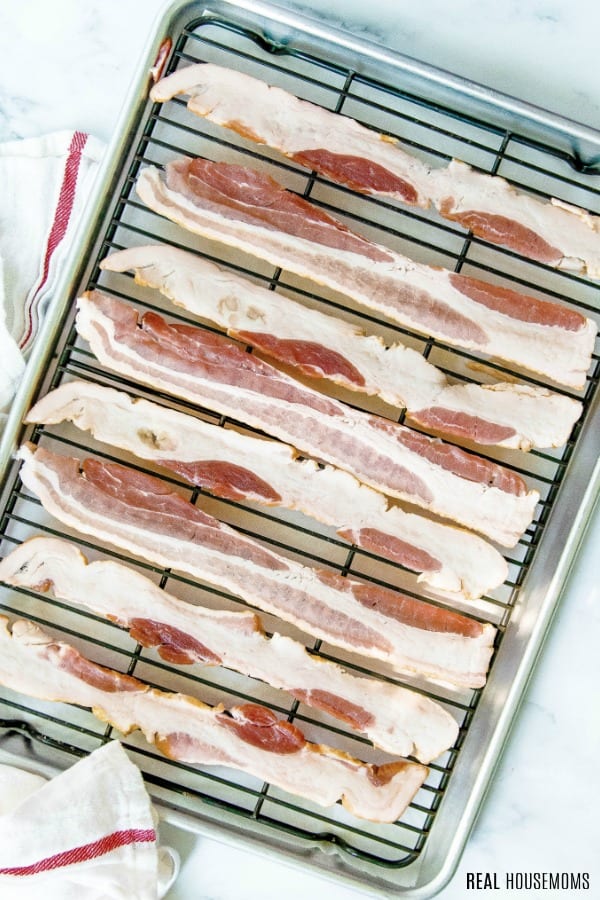 raw bacon strips on a baking rack