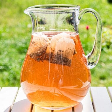 square image of a glass pitcher of brewed sun tea sitting outside
