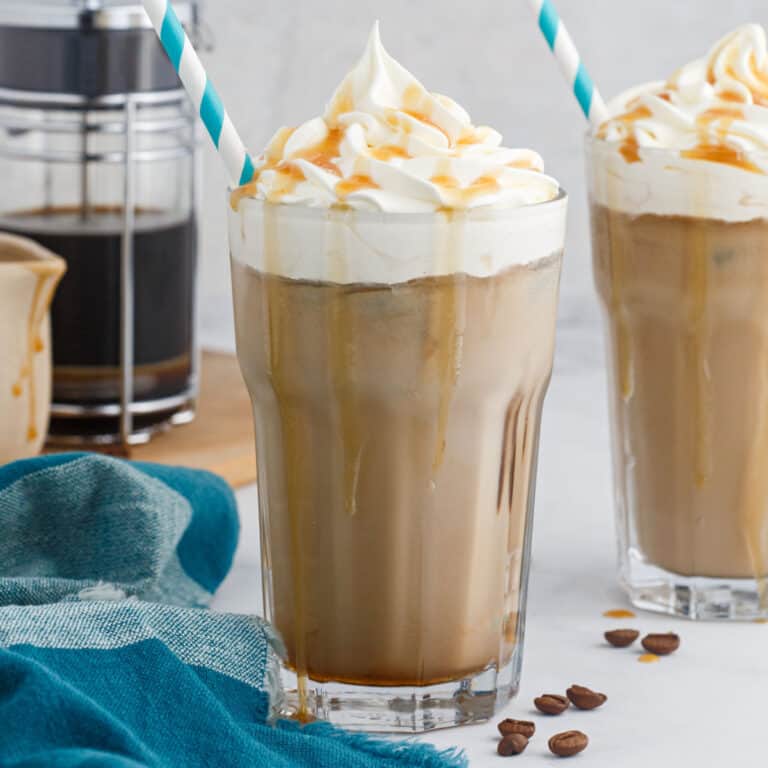 square image of an iced caramel macchiato in front of a french press
