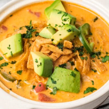 square image of chicken tortilla soup in a bowl with tortilla strips, avocado, and jalapeno