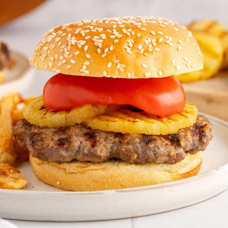 square image of an island teriyaki burger on a plate with fries